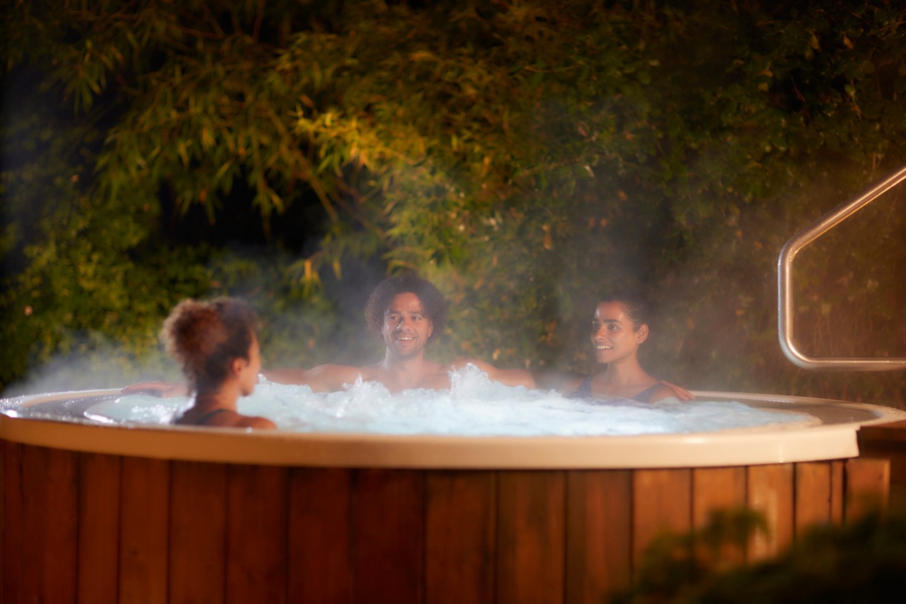 Men and women soaking in a bubbling outdoor hot tub.